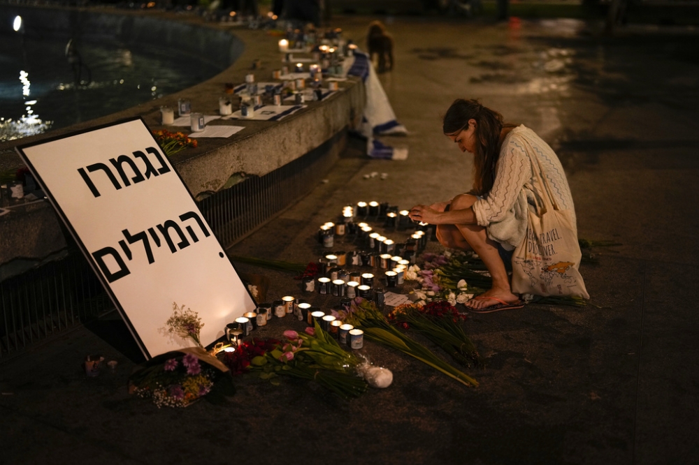 一名以色列婦女在特拉維夫哀悼死難者，上面寫著：「無言」。（美聯社）