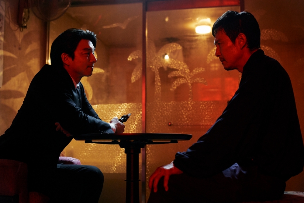 《魷魚遊戲：第2季》首批劇照釋出，孔劉（左）持槍與李政宰面對面而坐，臉上露出意味深長微笑，令人好奇後續發展。（Netflix提供）