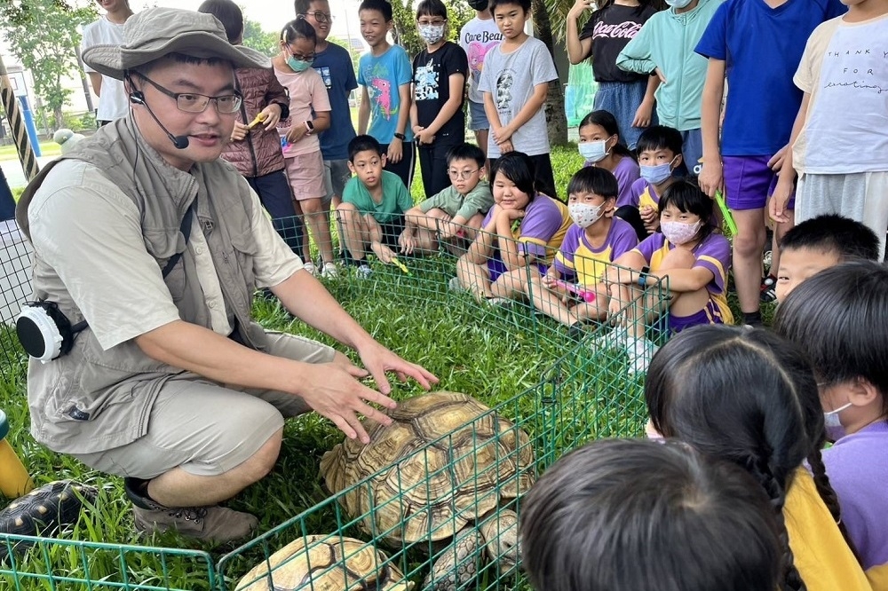 壽山動物園邀請「樣爸森友會」帶來陸龜、球蟒、守宮等爬蟲類動物，讓學童近距離觀察和互動。（觀光局提供）