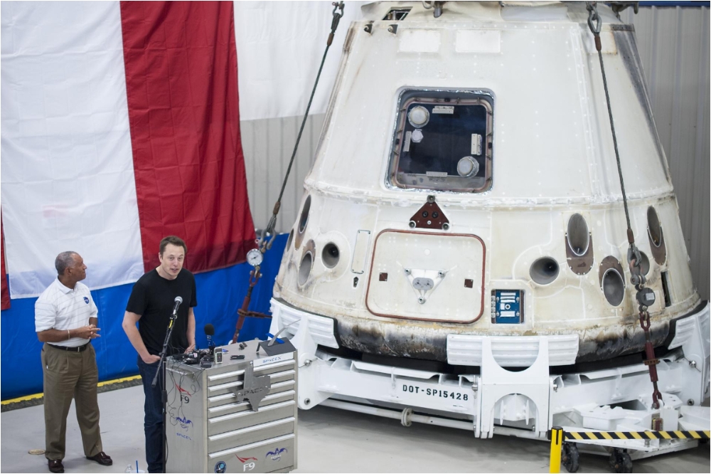 馬斯克2012年6月13日在SpaceX 位於德州的基地，慶祝乘龍號（背景）成功返回地球，完成第一次民間太空公司進行太空補給任務。（照片取自NASA）